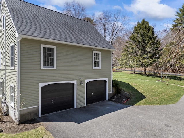 view of side of property featuring a yard, an attached garage, roof with shingles, and driveway