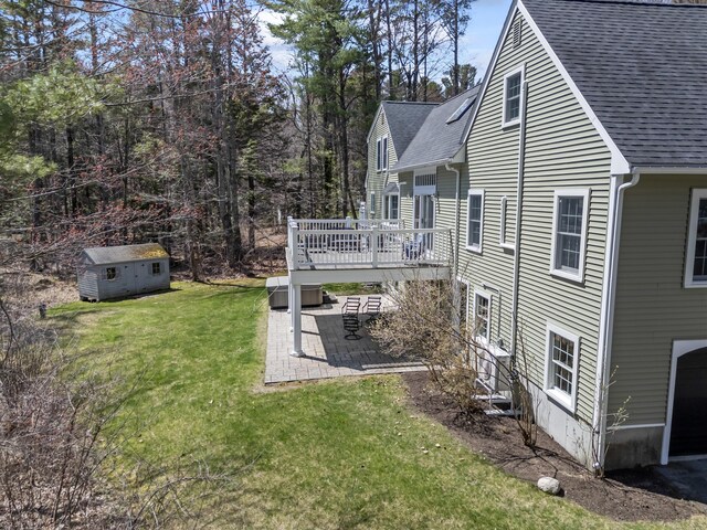 view of side of home featuring a yard, a patio area, roof with shingles, and a deck
