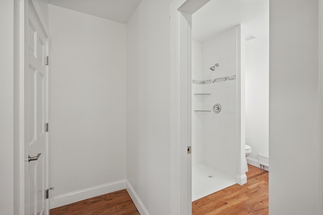 full bath featuring a stall shower, wood finished floors, toilet, and baseboards