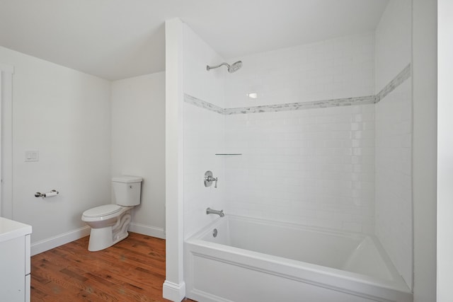 bathroom with toilet, wood finished floors,  shower combination, and baseboards