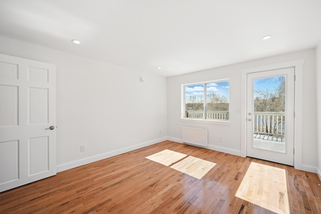 doorway featuring radiator heating unit, baseboards, wood finished floors, and recessed lighting