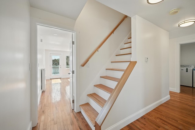 stairway featuring washer and dryer, hardwood / wood-style floors, baseboards, and radiator heating unit