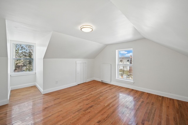 additional living space with light wood-style floors, baseboards, and lofted ceiling