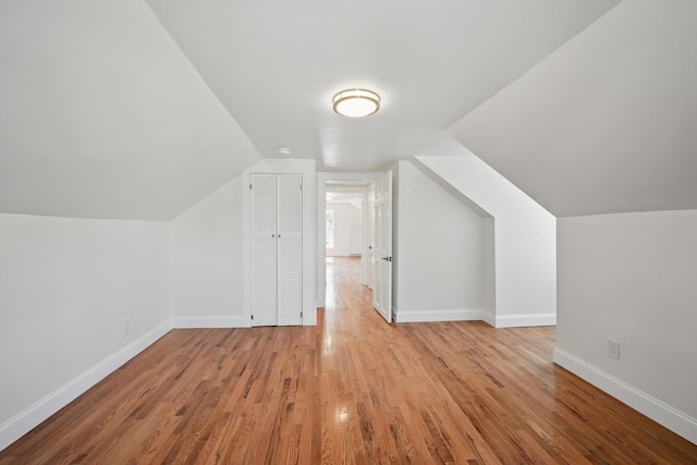 additional living space with wood finished floors, lofted ceiling, and baseboards