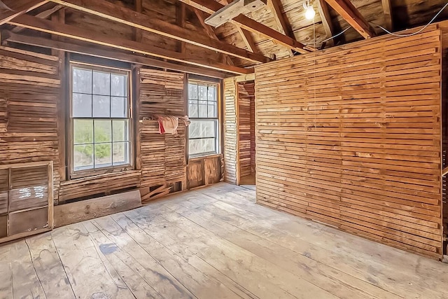 unfurnished room with wood walls, wooden ceiling, lofted ceiling with beams, and wood-type flooring