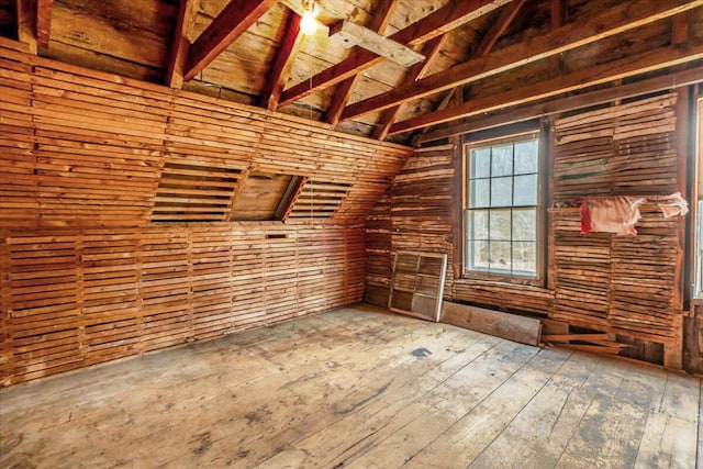 unfurnished room with wooden walls, hardwood / wood-style flooring, vaulted ceiling with beams, and wooden ceiling