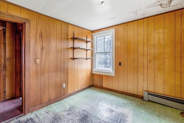 unfurnished room featuring baseboard heating, baseboards, and wooden walls
