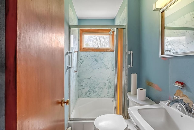 bathroom featuring combined bath / shower with glass door, toilet, and a sink