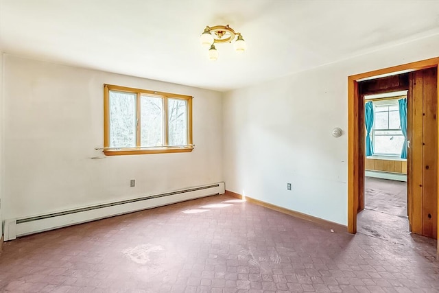 unfurnished room with baseboard heating, brick patterned floor, and baseboards