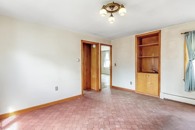 spare room featuring a baseboard heating unit and baseboards