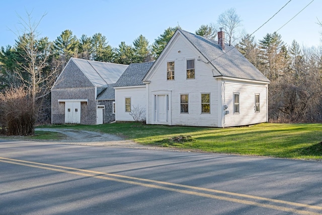 view of front facade featuring a front yard, a shingled roof, and a chimney