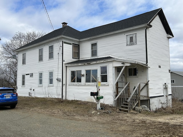 view of front of property with a shingled roof and a chimney