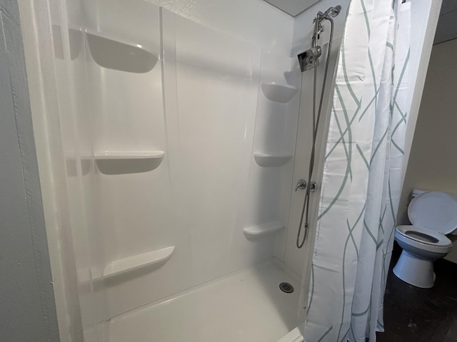 bathroom with a shower stall and toilet
