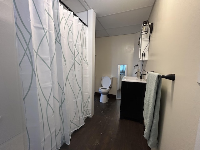 full bathroom with toilet, vanity, wood finished floors, and a drop ceiling