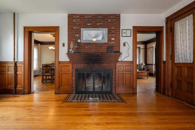 546 Main St, Westbrook, ME 04092 - living room featuring hardwood / wood-style floors, wainscoting, a fireplace, ornamental molding, and a chandelier
