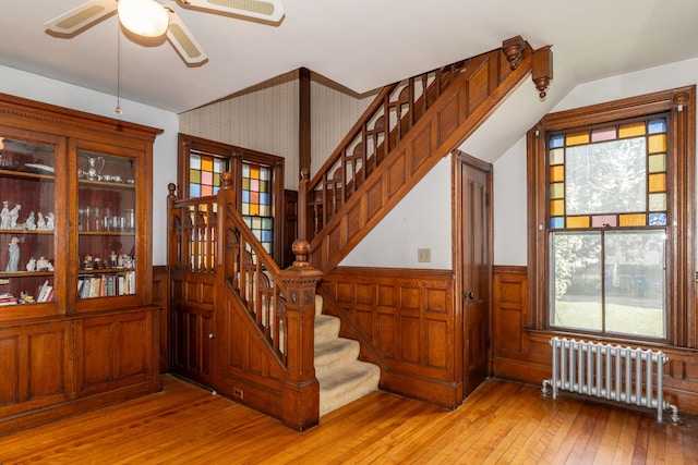 546 Main St, Westbrook, ME 04092 - stairway featuring radiator heating unit, a wainscoted wall, wood-type flooring, a ceiling fan, and plenty of natural light