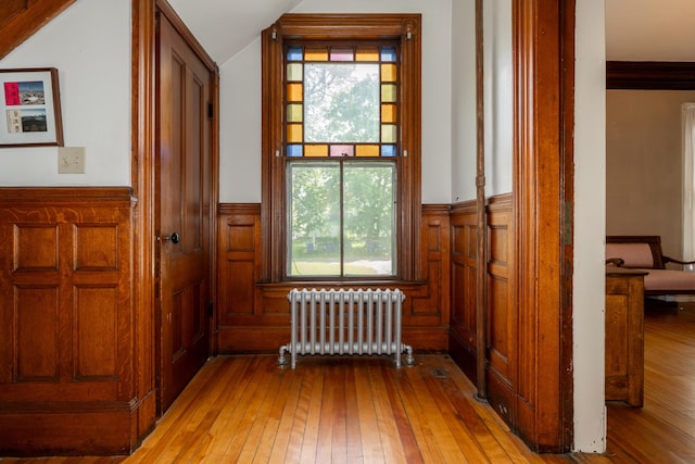 546 Main St, Westbrook, ME 04092 - hallway with radiator heating unit, wainscoting, light wood-style floors, healthy amount of natural light, and vaulted ceiling