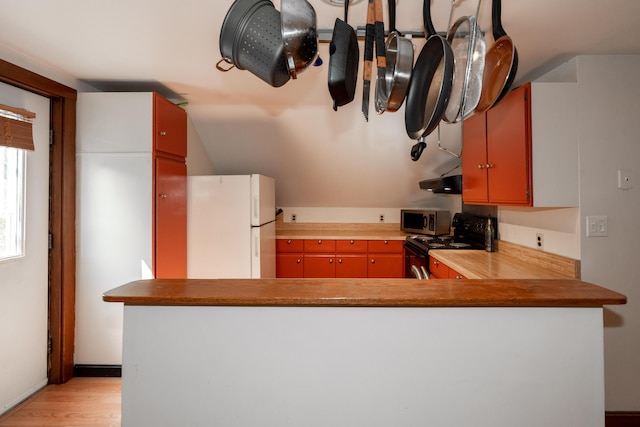 546 Main St, Westbrook, ME 04092 - kitchen with freestanding refrigerator, black electric range, stainless steel microwave, light wood-style flooring, and ventilation hood