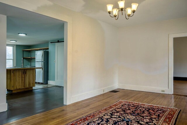 6 Naskeag Rd, Brooklin, ME 04616 - unfurnished dining area featuring hardwood / wood-style flooring, a barn door, visible vents, an inviting chandelier, and baseboards