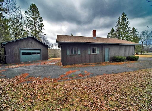 view of side of home featuring a chimney, an outdoor structure, and a detached garage