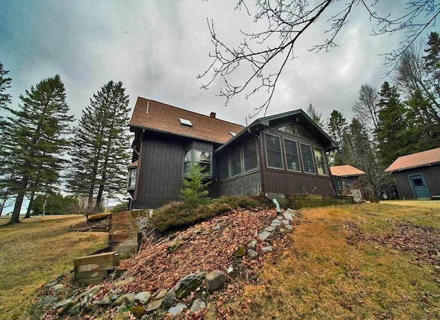 view of side of property featuring a sunroom, a yard, and stairway