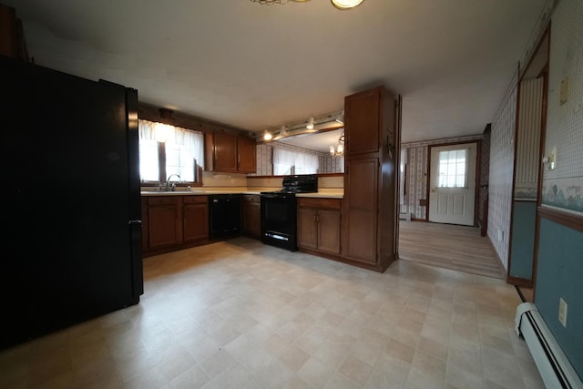 kitchen featuring light floors, light countertops, a sink, black appliances, and a baseboard radiator