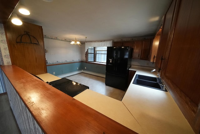 kitchen featuring wallpapered walls, a sink, black appliances, a chandelier, and baseboard heating
