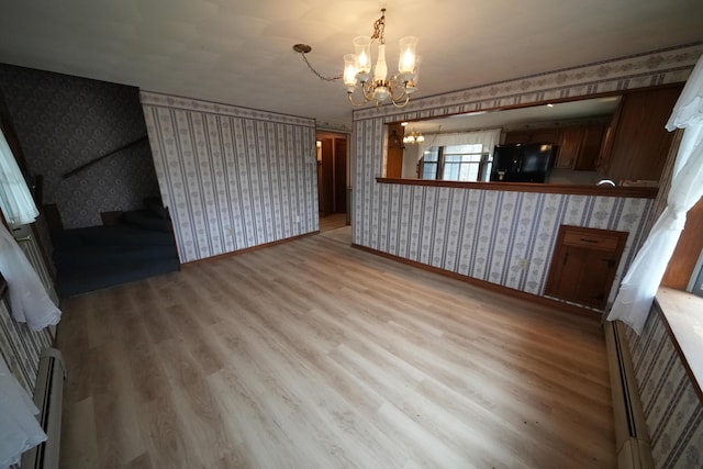 unfurnished living room featuring wallpapered walls, stairway, wood finished floors, baseboards, and a chandelier