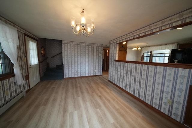 interior space featuring a baseboard heating unit, wallpapered walls, wood finished floors, and a notable chandelier