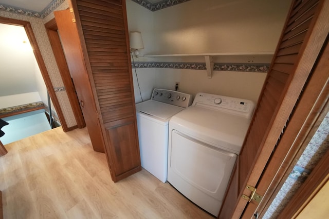 clothes washing area with separate washer and dryer, light wood-style floors, and laundry area