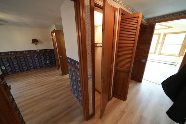 corridor with baseboard heating, wallpapered walls, an upstairs landing, and light wood finished floors