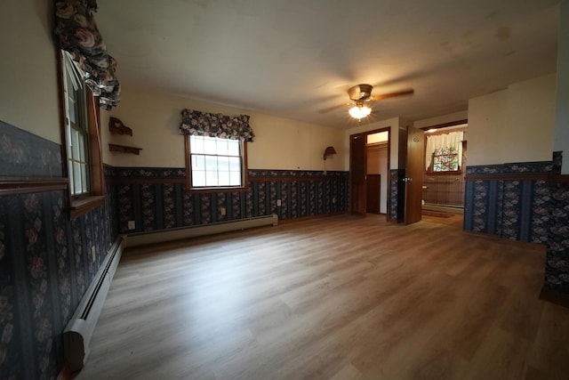 unfurnished living room with wainscoting, wallpapered walls, wood finished floors, and ceiling fan