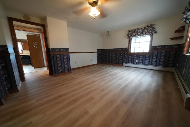 interior space with wood finished floors, baseboards, ceiling fan, and wainscoting