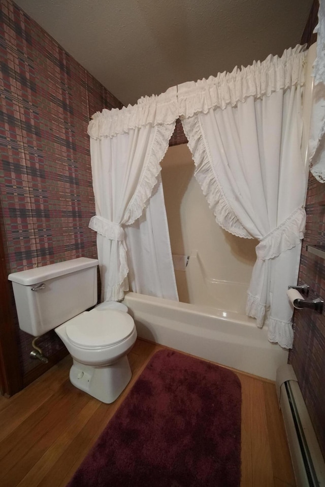 bathroom with a baseboard radiator, wood finished floors, shower / bath combo with shower curtain, and toilet