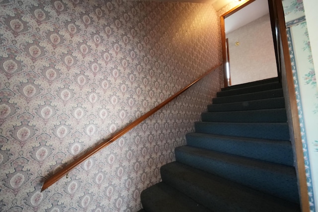 stairs featuring wallpapered walls