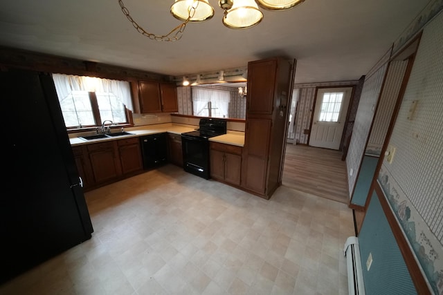 kitchen featuring a sink, wallpapered walls, a chandelier, light floors, and electric range