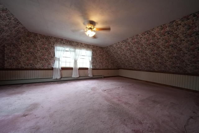 additional living space with a baseboard heating unit, wallpapered walls, a wainscoted wall, and ceiling fan