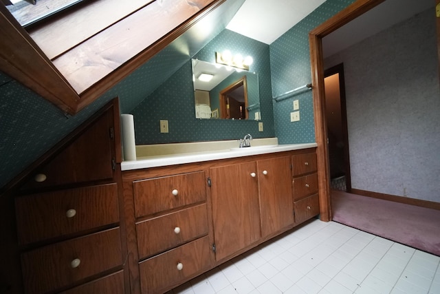 bathroom with vaulted ceiling, vanity, wallpapered walls, and baseboards