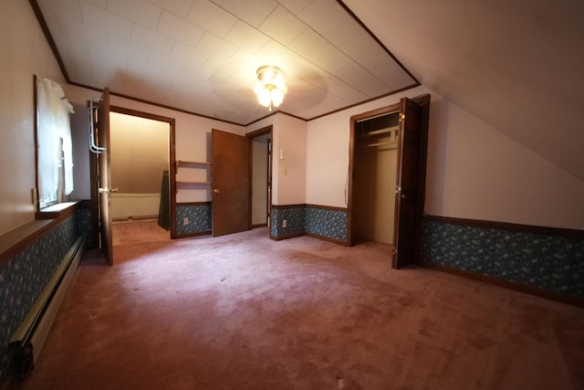 unfurnished bedroom featuring a wainscoted wall, vaulted ceiling, a baseboard heating unit, a closet, and carpet flooring
