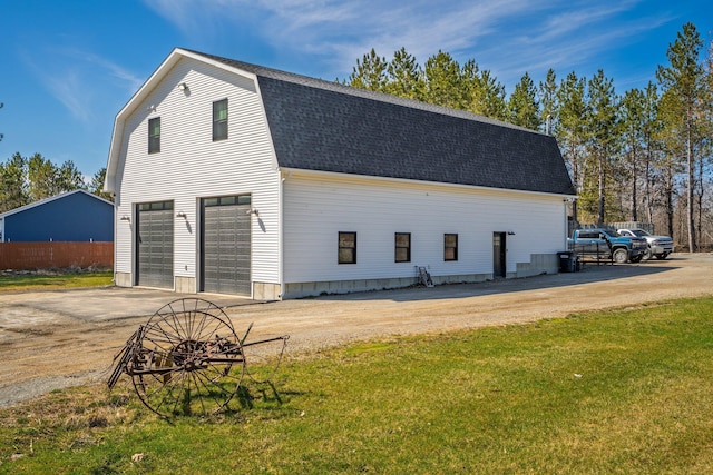 exterior space with driveway, a yard, a gambrel roof, and a shingled roof