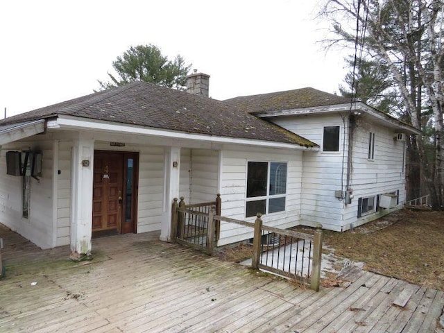 view of front of home featuring a chimney, a deck, and a shingled roof