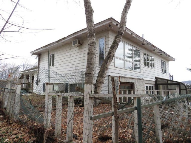 view of side of property featuring fence and an AC wall unit