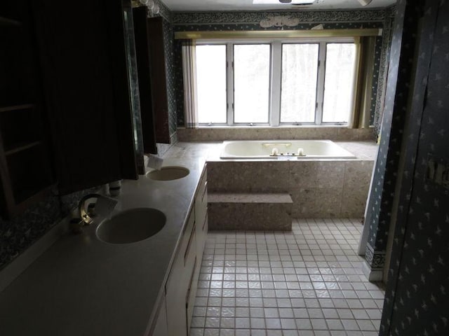 bathroom with tile patterned flooring, wallpapered walls, a garden tub, and a sink
