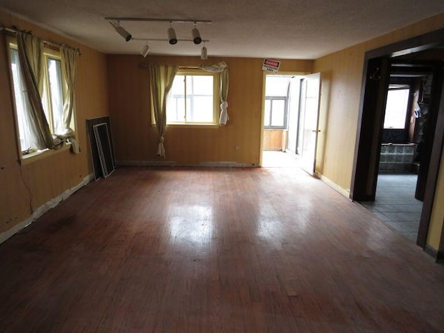 empty room featuring track lighting, baseboards, and wood finished floors