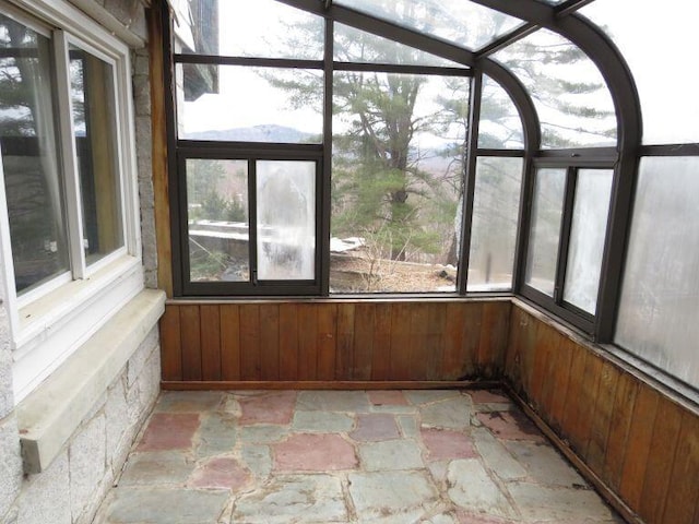 unfurnished sunroom with wooden walls and stone floors