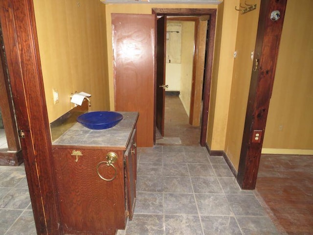 hall featuring baseboards and a sink
