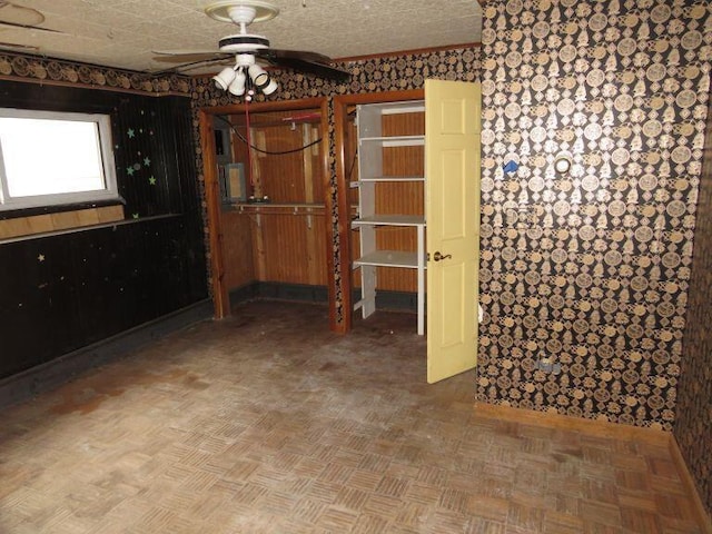 spare room featuring wallpapered walls, a ceiling fan, and baseboards