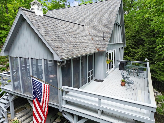 wooden terrace featuring a sunroom and outdoor dining space