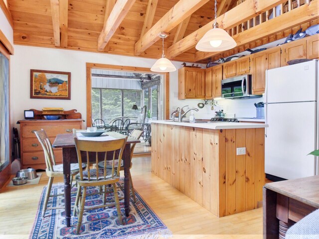 kitchen featuring stainless steel microwave, light countertops, freestanding refrigerator, and light wood-style floors