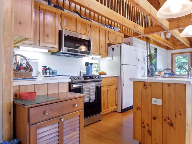 kitchen featuring light wood-style flooring, a sink, appliances with stainless steel finishes, and light countertops